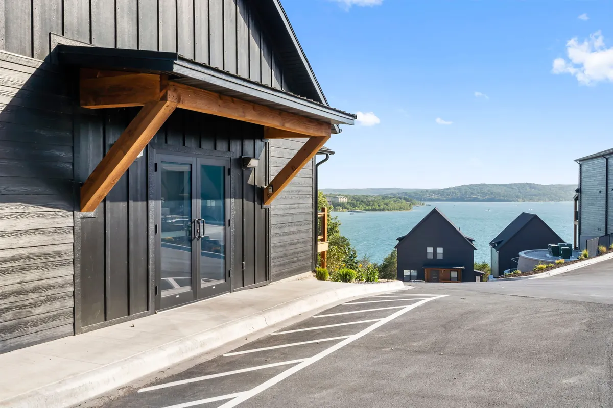 A modern home with wood and glass architectural features set against a tranquil waterfront landscape. The setting suggests opportunities for relaxing by the shore, outdoor gatherings, and exploring the natural beauty surrounding the property, reinforcing the privacy and community aspects mentioned in the section.