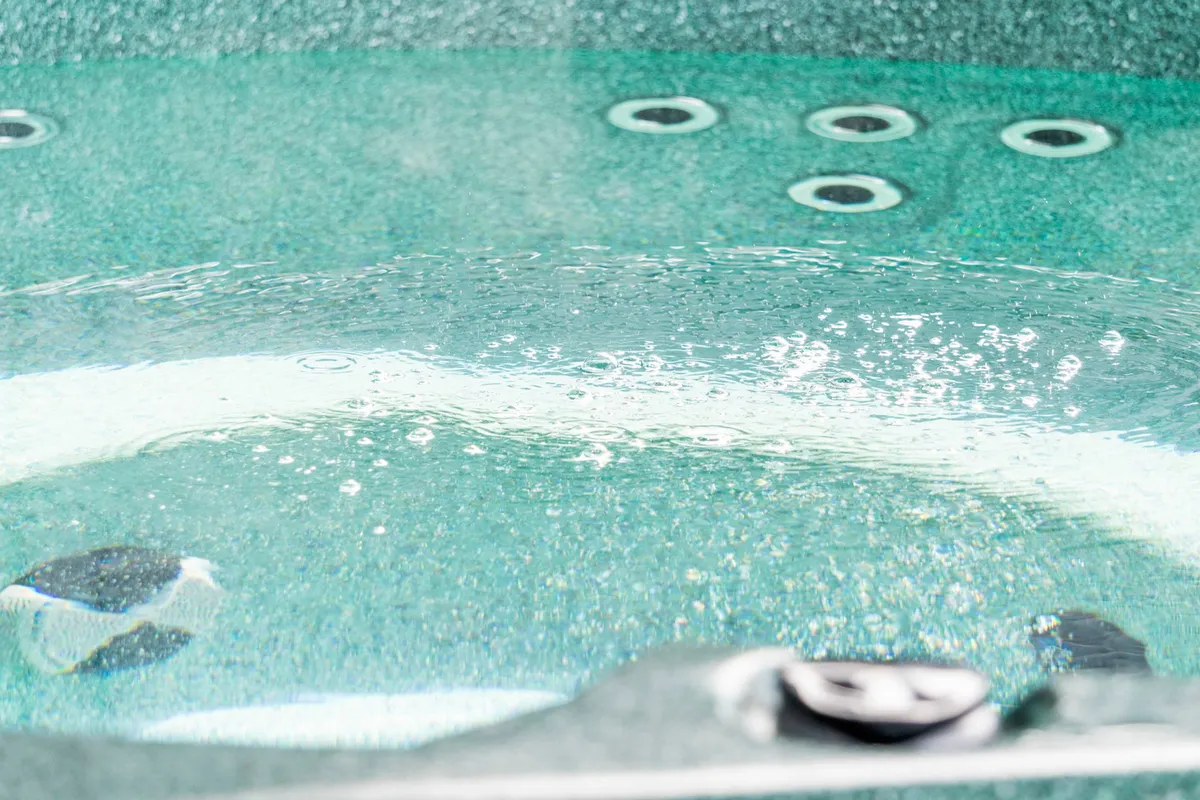 A detailed view of a bubbling hot tub, with tranquil water inviting guests for a luxurious soak. The composition focuses on the relaxing, spa-like quality of the hot tub experience.