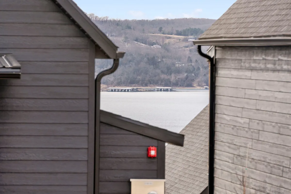 A wide exterior view showcasing rooftops of neighboring buildings with a stunning lake visible in the background. The mood is calm and serene, perfect for relaxing by the water or enjoying sunset views and quiet moments outdoors.