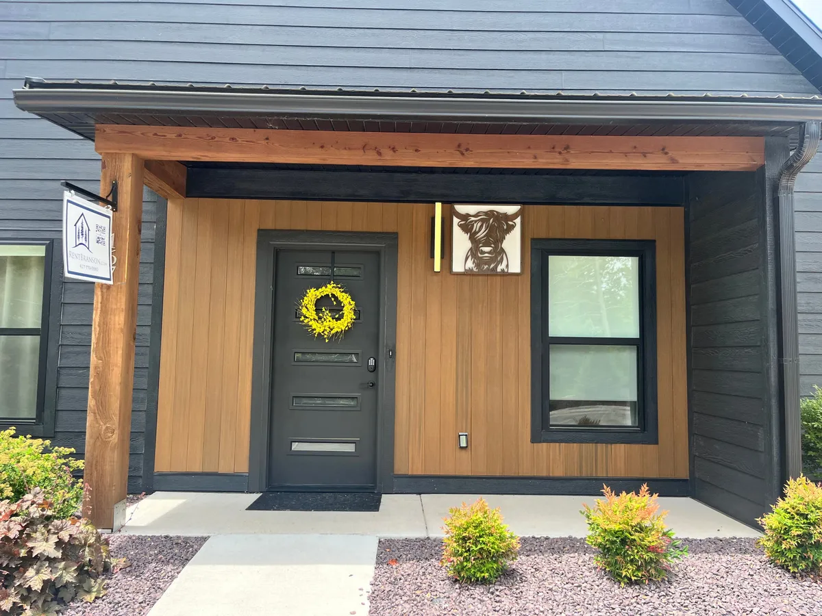 A close-up of the entrance with a cheerful yellow wreath and local artwork, including a distinctive cow painting. Wooden beams frame the door, evoking a rustic and welcoming first impression.