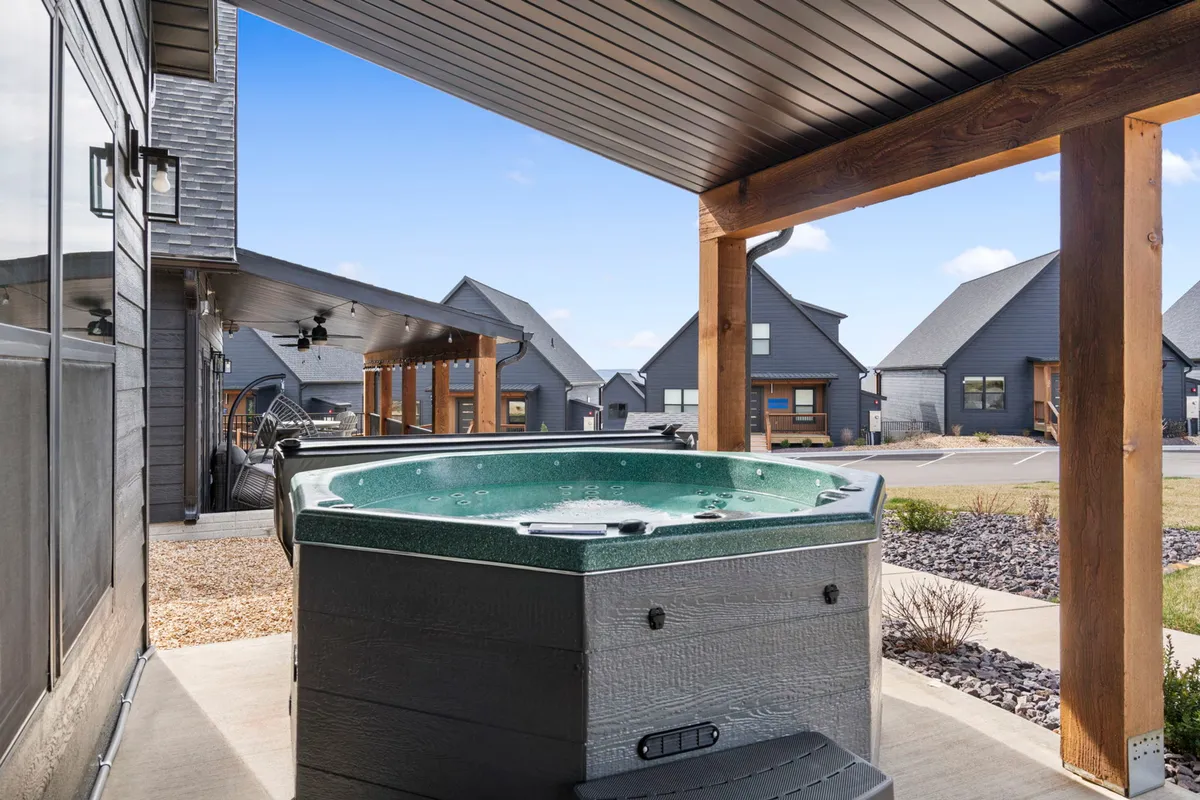 An exterior view showing the hot tub surrounded by inviting patio seating and attractive architecture. The scene captures a sense of relaxation and connection to the outdoors, with ample space for unwinding alone or with company.