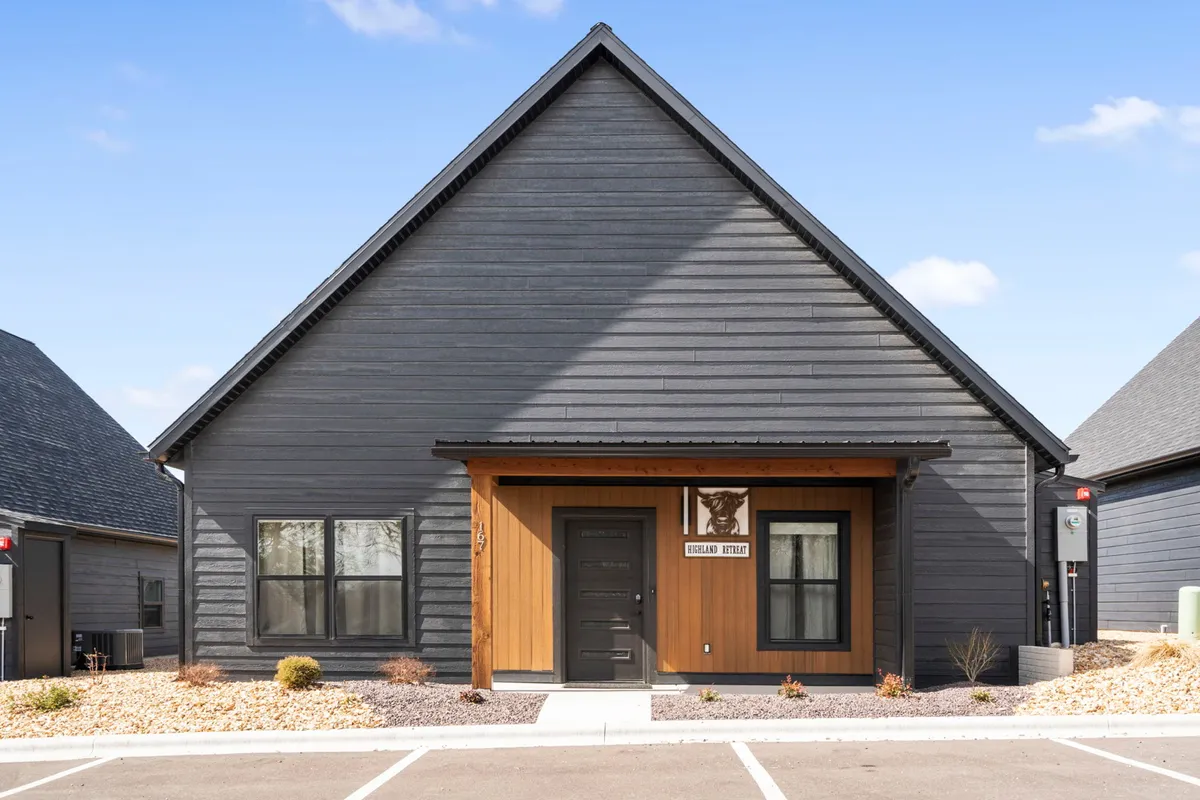A broader exterior shot showcasing the home's front door, wooden accents, and the surrounding porch area. The scene hints at opportunities for outdoor relaxation, family gatherings, and enjoying community events, set against an inviting color scheme.