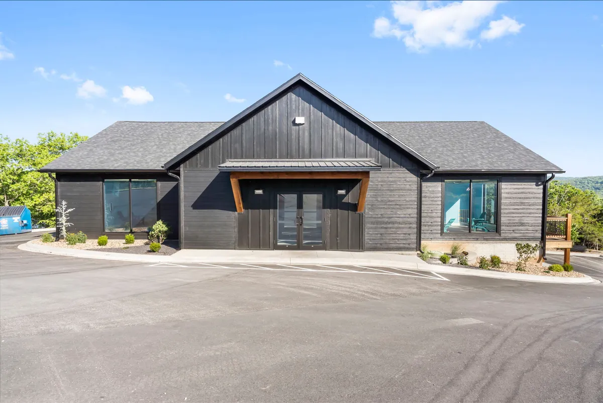 A striking exterior shot of Huckleberry Highland, featuring modern architectural design with large glass windows and wood accents. The building sits amidst natural surroundings, creating a tranquil and inviting first impression.