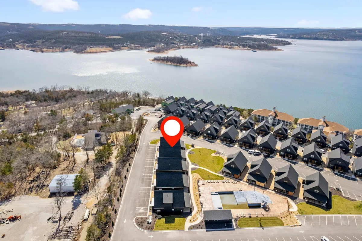 A wide, scenic view of Table Rock Lake with a row of community buildings along the shoreline and a natural landscape stretching into the distance. The image evokes outdoor activities such as boating, hiking, and picnicking, with a sunset casting a golden glow over the water.