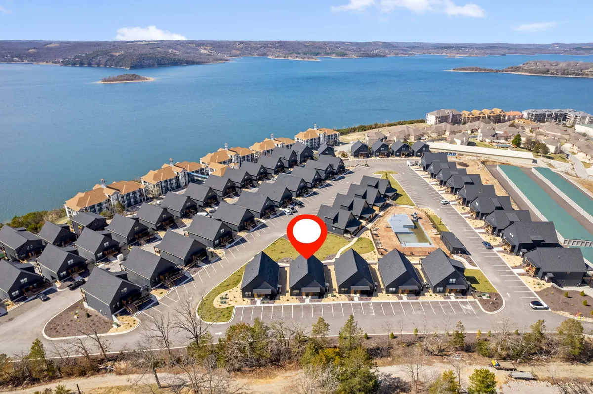 A tranquil lakeside scene showing a cluster of inviting houses with landscaped lawns, set against the backdrop of Table Rock Lake. The soft lighting suggests a relaxing mood, ideal for morning coffee on the deck or campfire evenings by the water.